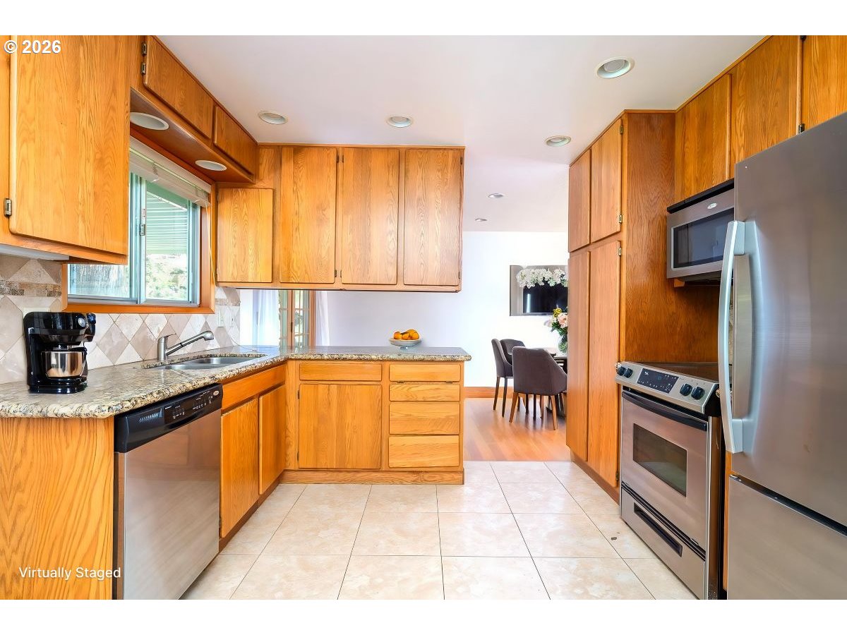 5815 Southwest Huddleson Street Portland, OR 97219 - Photo 7 of 35 a kitchen with stainless steel appliances granite countertop a stove a sink and a refrigerator