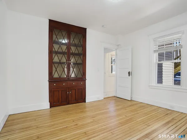 a view of an empty room with wooden floor and window