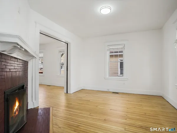 a view of empty room with wooden floor and fireplace