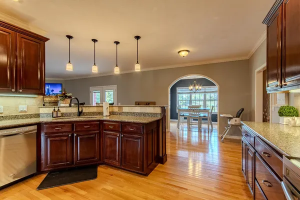 a kitchen with stainless steel appliances kitchen island granite countertop a stove a refrigerator a kitchen island a dining table and chairs with wooden floor