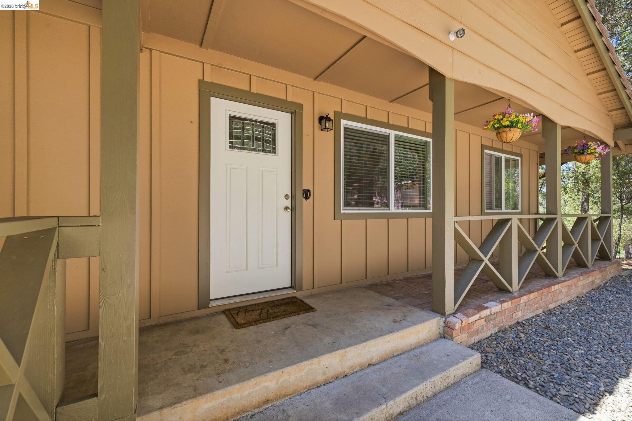 19059 Raboul Court Groveland, CA 95321 - Photo 4 of 21 Front porch entry featuring a white door with decorative glass, board-and-batten siding, concrete steps, and a decorative railing with brick base
