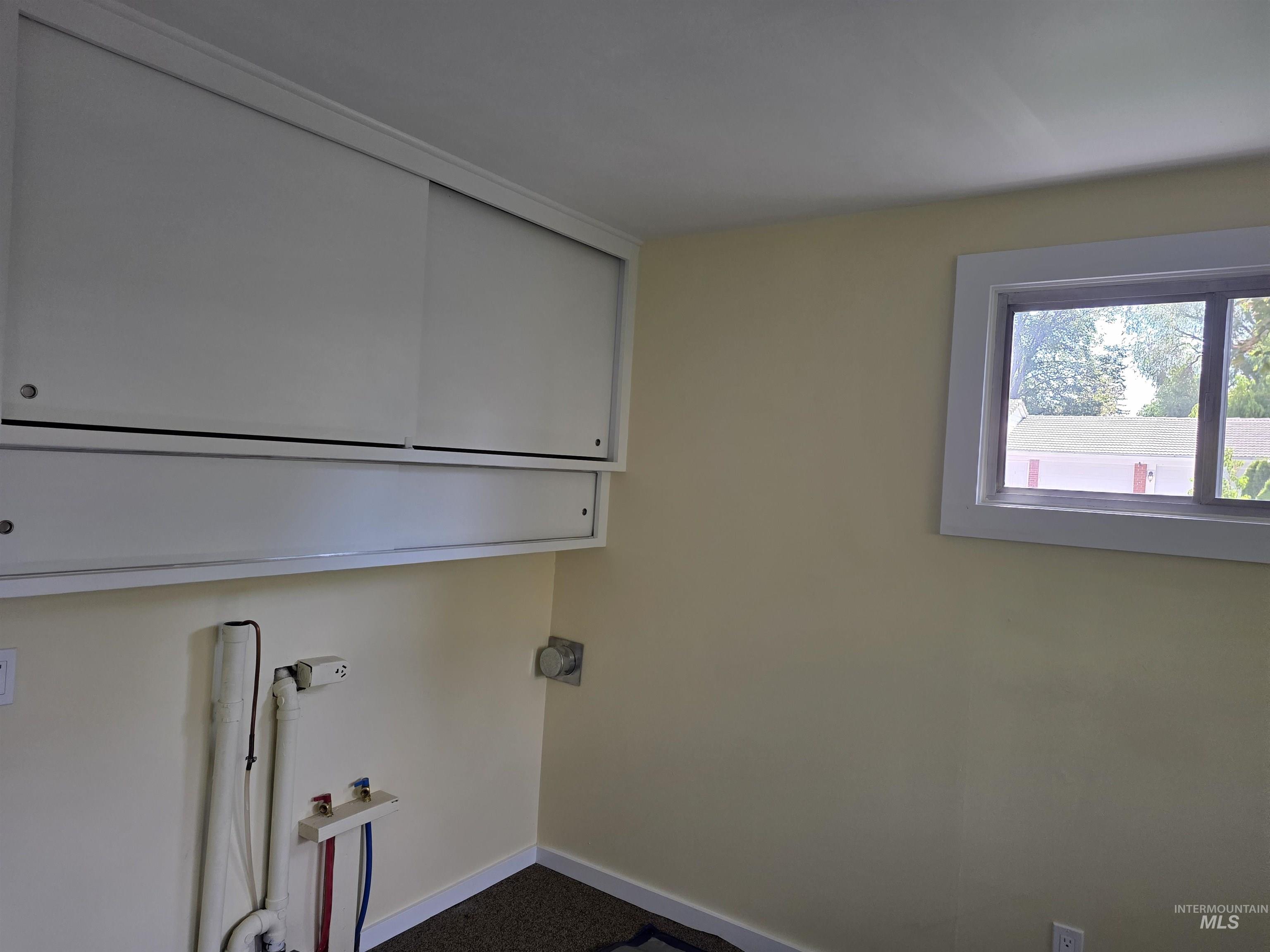 421 East Main Street Jerome, ID 83338 - Photo 11 of 13 Room featuring wood paneling on walls and ceiling, wood-finish flooring, built-in cabinetry with drawers, and a window with blinds