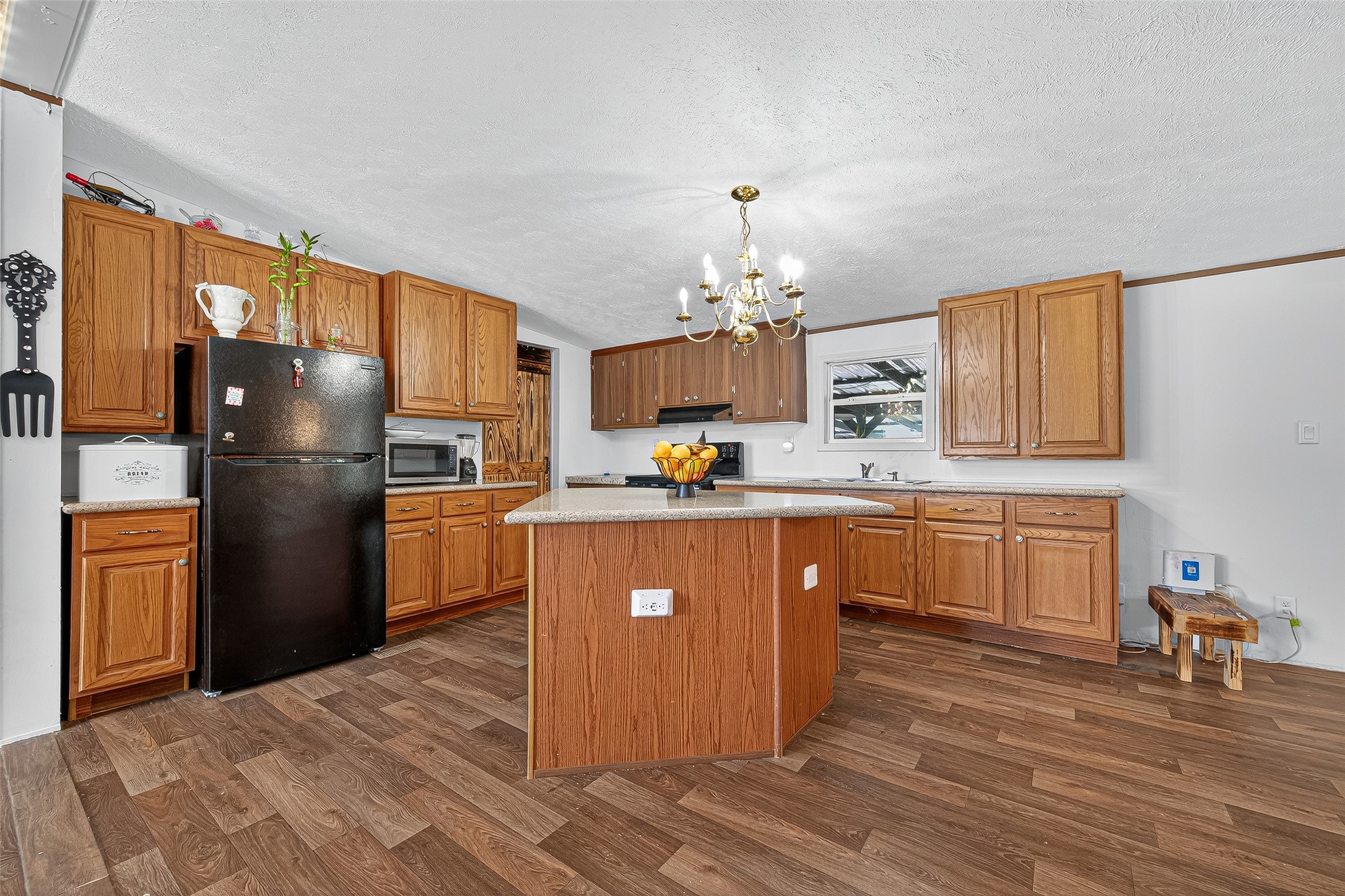 12514 County Road 3740 Cleveland, TX 77327 - Photo 8 of 31 a kitchen with a refrigerator a kitchen island a stove a sink cabinets and a dining table