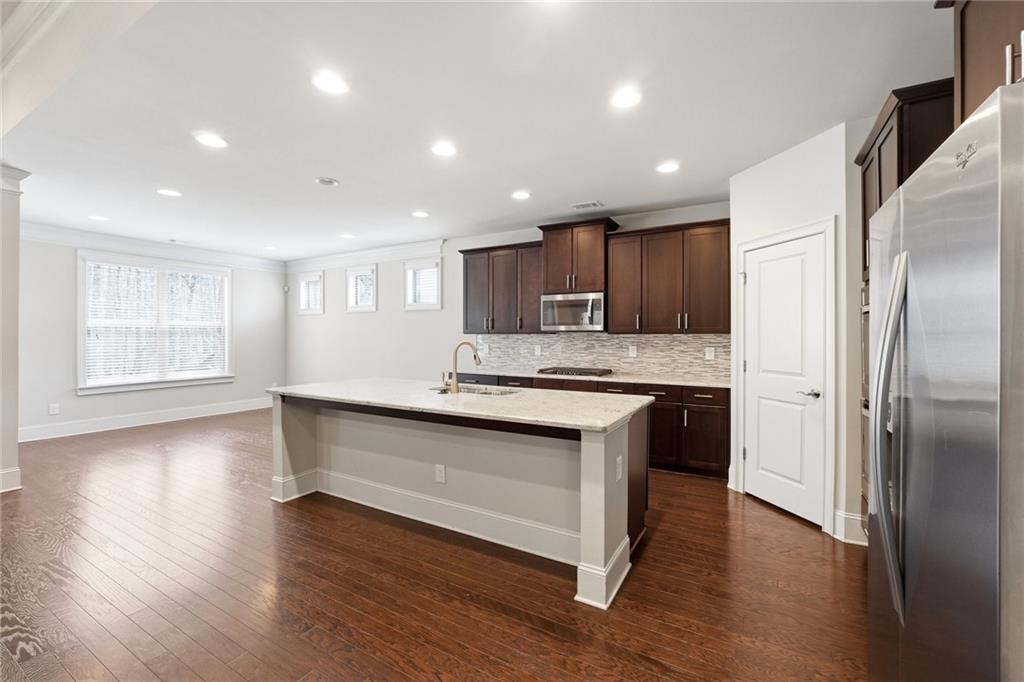 1810 Geranium Lane Cumming, GA 30040 - Photo 20 of 37 a kitchen with stainless steel appliances granite countertop a refrigerator a sink a stove and oven with wooden floors
