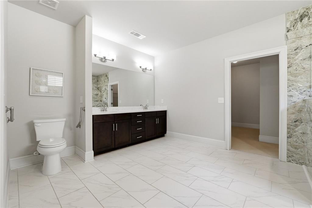 1810 Geranium Lane Cumming, GA 30040 - Photo 28 of 37 a spacious bathroom with a granite countertop sink a toilet and a mirror