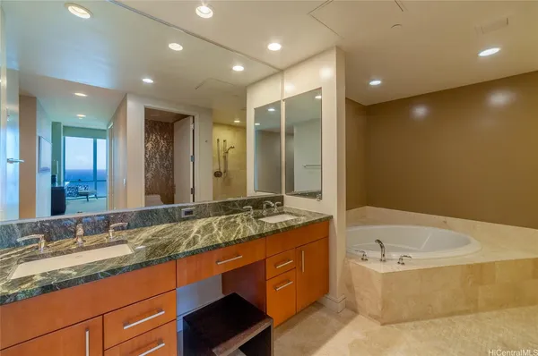 a bathroom with a granite countertop tub sink and mirror