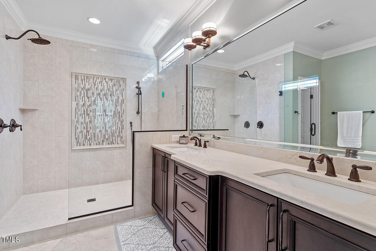 2016 Brassfield Road Raleigh, NC 27614 - Photo 19 of 44 a bathroom with a double vanity sink a large mirror a shower and a bathtub