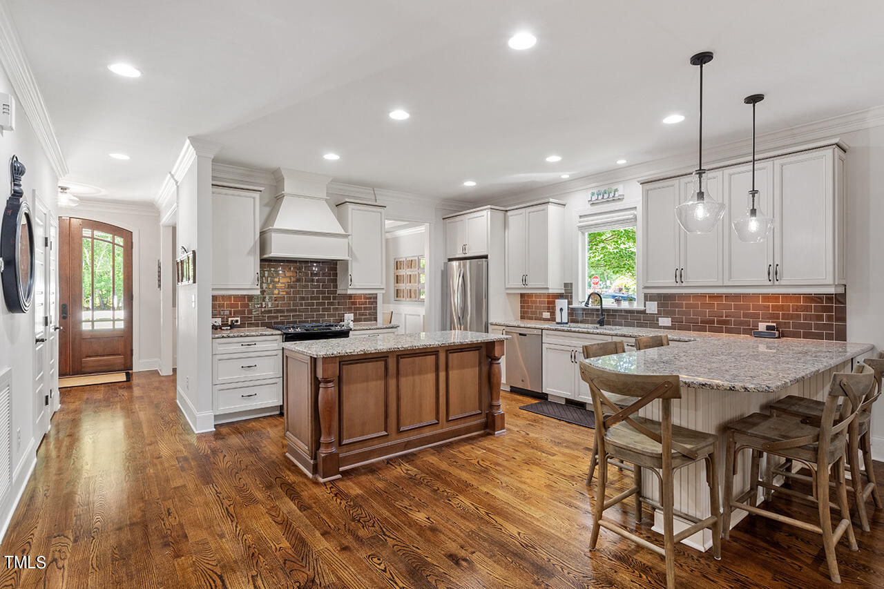 2016 Brassfield Road Raleigh, NC 27614 - Photo 9 of 44 a kitchen with stainless steel appliances kitchen island granite countertop a stove a sink a refrigerator and white cabinets with wooden floor