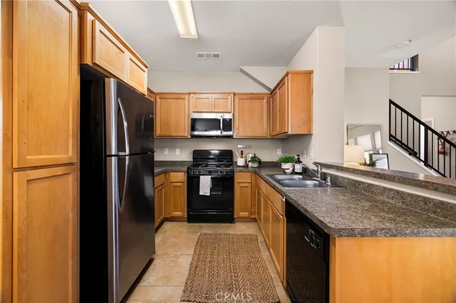 a kitchen with stainless steel appliances granite countertop a refrigerator a stove a sink and a microwave