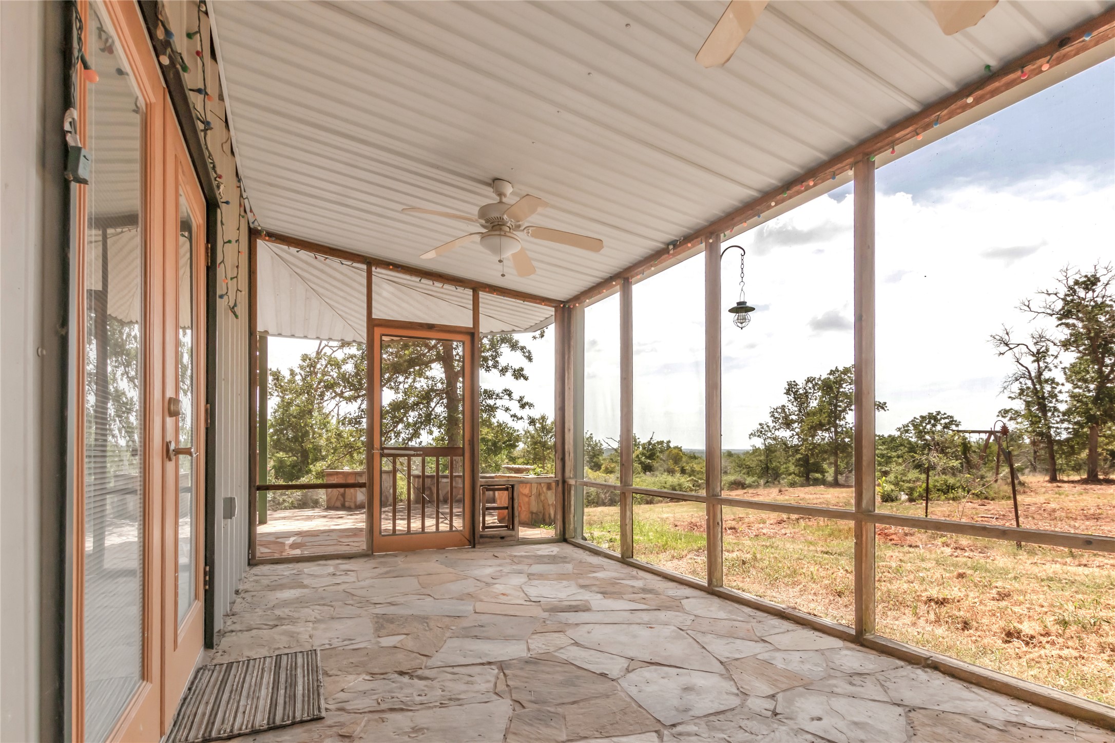1004 22 Hills Road Gause, TX 77857 - Photo 35 of 37 An inviting screened porch with natural stone flooring offers serene views of the surrounding landscape.