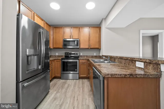 a kitchen with stainless steel appliances granite countertop a refrigerator a stove and a sink