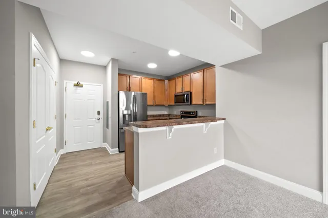 a view of kitchen with refrigerator cabinets and wooden floor