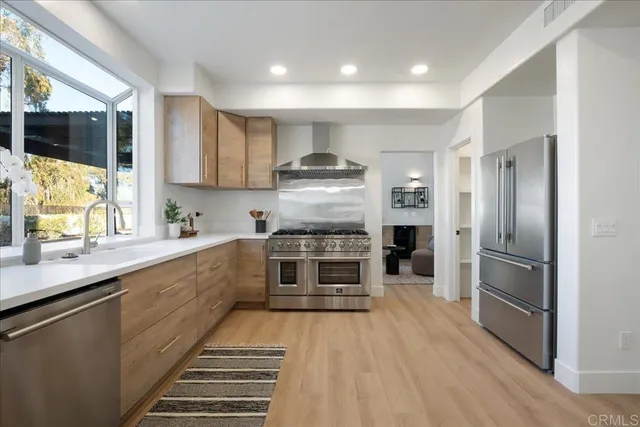 a kitchen with granite countertop a refrigerator oven a sink dishwasher and white cabinets with wooden floor