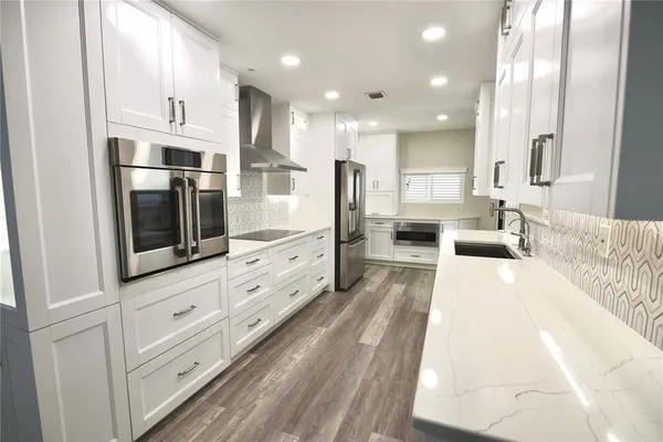 a large white kitchen with stainless steel appliances and cabinets