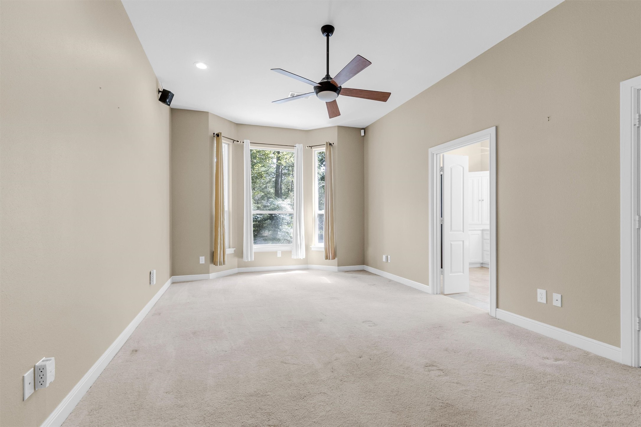 10331 Iron Ore Road Conroe, TX 77303 - Photo 14 of 47 Spacious bedroom with neutral tones, featuring a large bay window that floods the room with natural light, and an adjoining bathroom for added convenience.