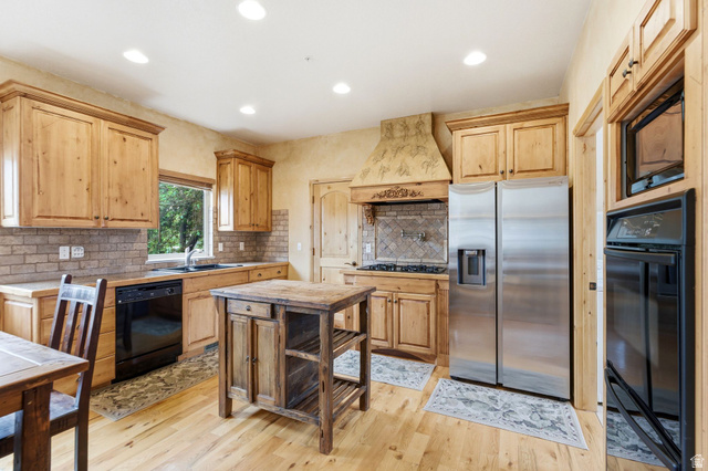 3634 North Huntsman Path, Unit C203 Eden, UT 84310 - Photo 4 of 27 Kitchen featuring light wood cabinetry, a decorative range hood, stainless steel side-by-side refrigerator, and hardwood flooring
