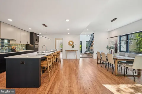 a kitchen with stainless steel appliances kitchen island granite countertop a table chairs in it and wooden floors