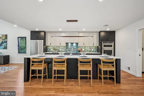 a kitchen with a dining table chairs and wooden floor
