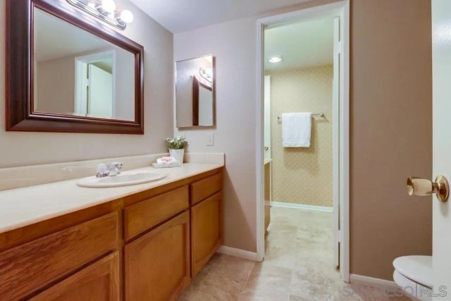 a bathroom with a double vanity sink and mirror with toilet
