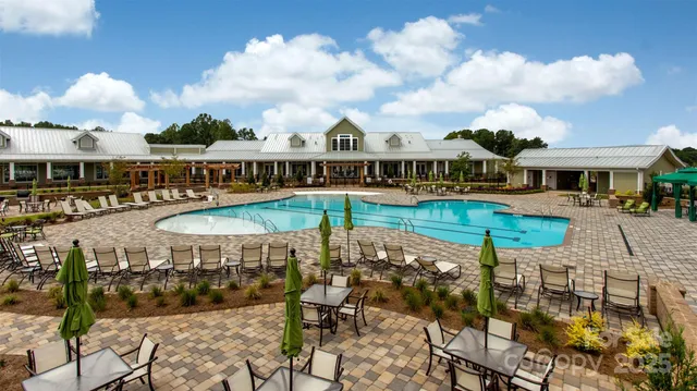 a view of a swimming pool with lawn chairs potted plants