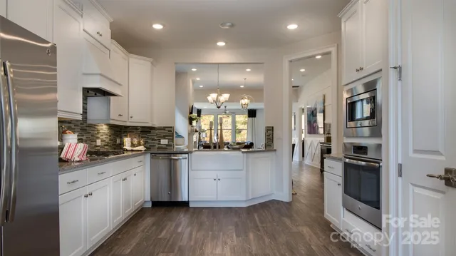 a kitchen with stainless steel appliances granite countertop a refrigerator a stove and a sink