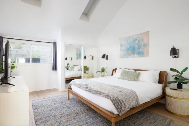 a bedroom with a large bed and a potted plant