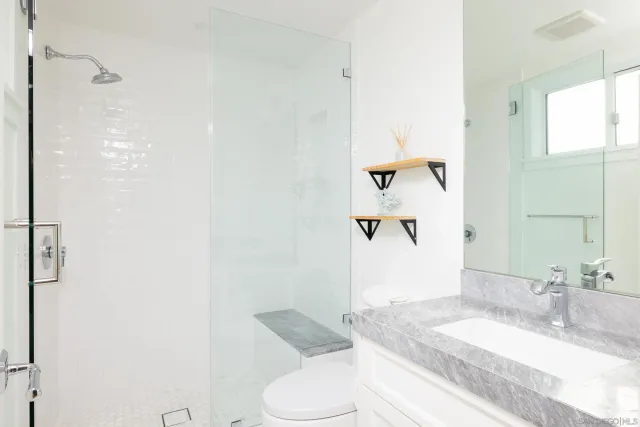 a bathroom with a granite countertop sink mirror vanity and toilet