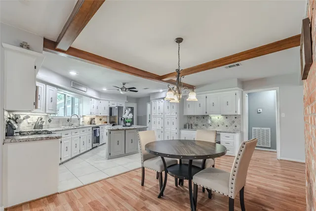 a kitchen with a dining table chairs stainless steel appliances and cabinets