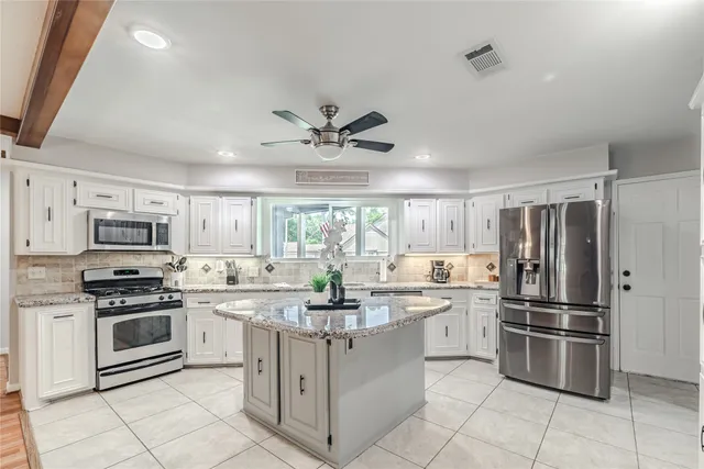 a kitchen with stainless steel appliances granite countertop a refrigerator a sink dishwasher a stove and white cabinets