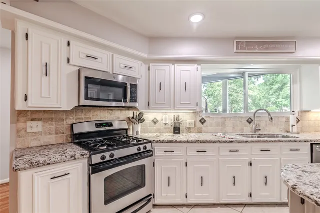 a kitchen with stainless steel appliances granite countertop a sink a stove a microwave and wooden cabinets