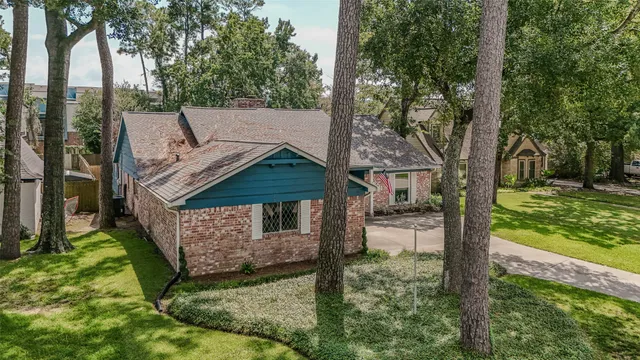 a view of a house with a small yard and large tree
