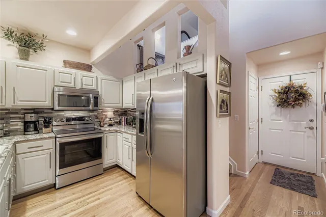 a kitchen with stainless steel appliances granite countertop a refrigerator and a stove top oven