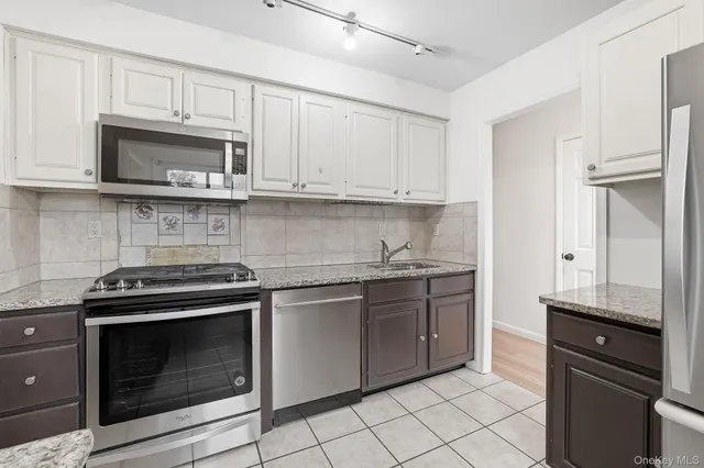a kitchen with stainless steel appliances granite countertop a stove a sink and a microwave
