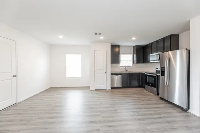 a large kitchen with a center island wooden floor and stainless steel appliances