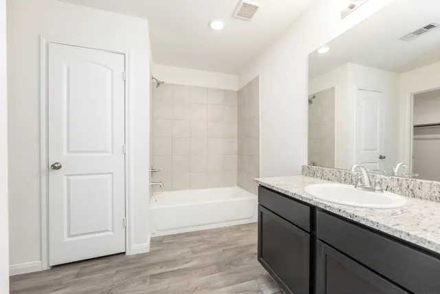a bathroom with a granite countertop sink a mirror and a bathtub