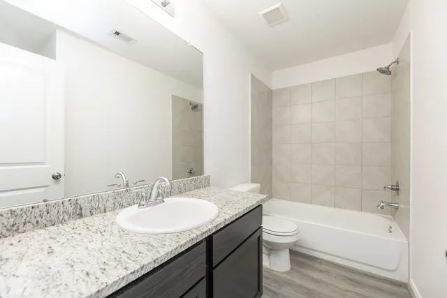 a bathroom with a granite countertop sink toilet and shower