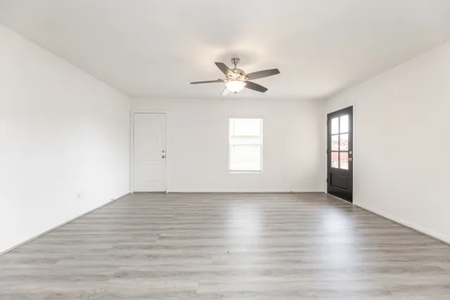 an empty room with wooden floor and windows