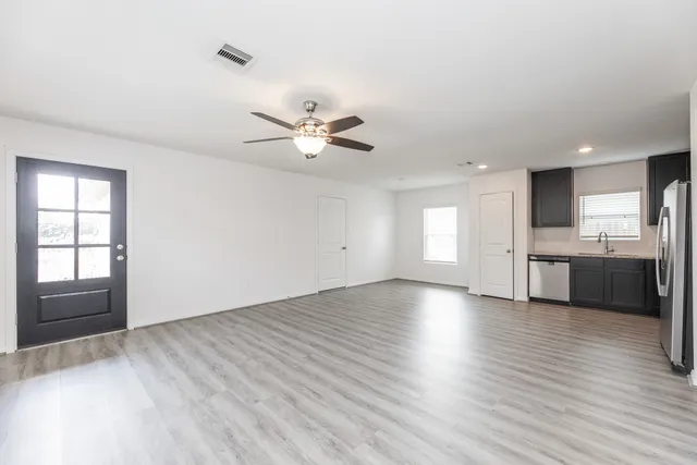 an empty room with wooden floor and a kitchen