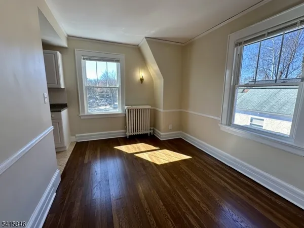 a view of wooden floor in an empty room with a window