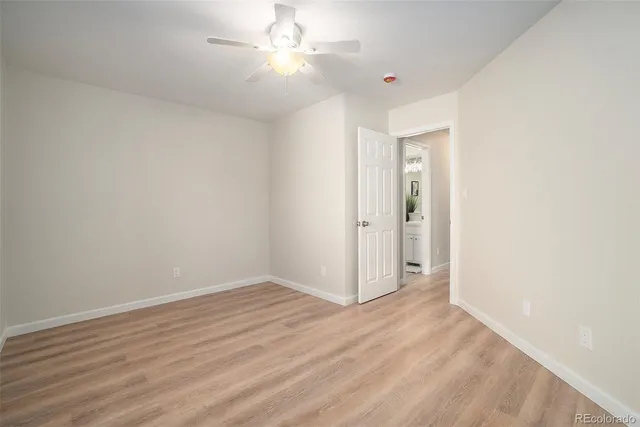 an empty room with wooden floor chandelier fan and windows