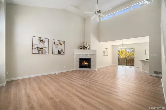 an empty room with wooden floor fireplace and windows