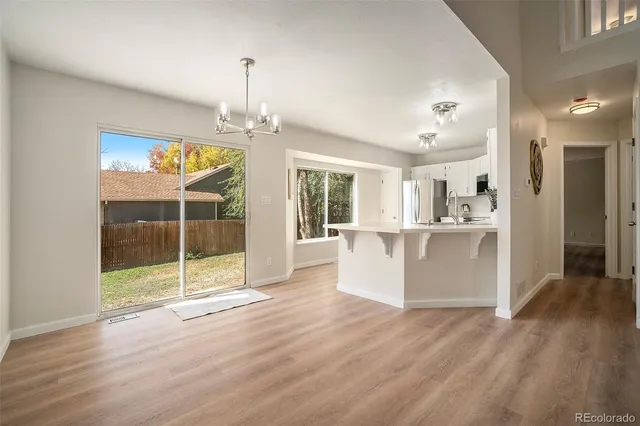 a view of kitchen with stainless steel appliances granite countertop a stove top oven a refrigerator a sink and dishwasher with wooden floor