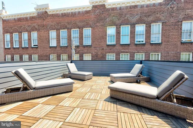 a view of a patio with couches and a dining table and chairs with wooden floor