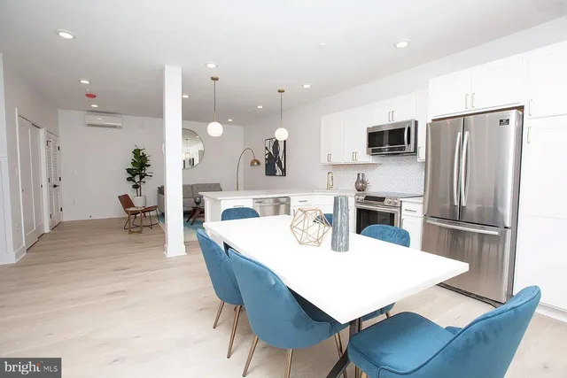 a kitchen with a dining table chairs refrigerator and microwave