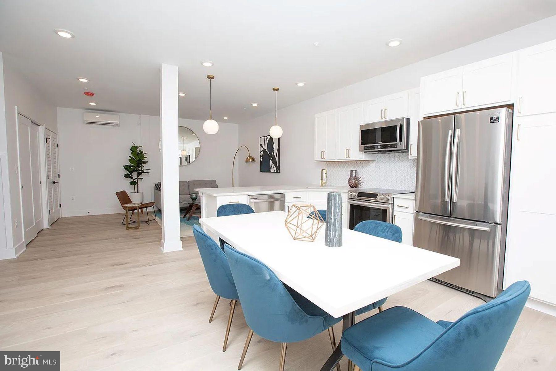 1617 Eastern Avenue, Unit 201 Baltimore, MD 21231 - Photo 2 of 13 a kitchen with a dining table chairs refrigerator and microwave