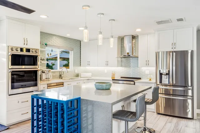 a kitchen with stainless steel appliances a stove a sink a microwave a refrigerator and cabinets