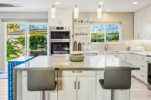 a kitchen with kitchen island granite countertop a sink and a refrigerator