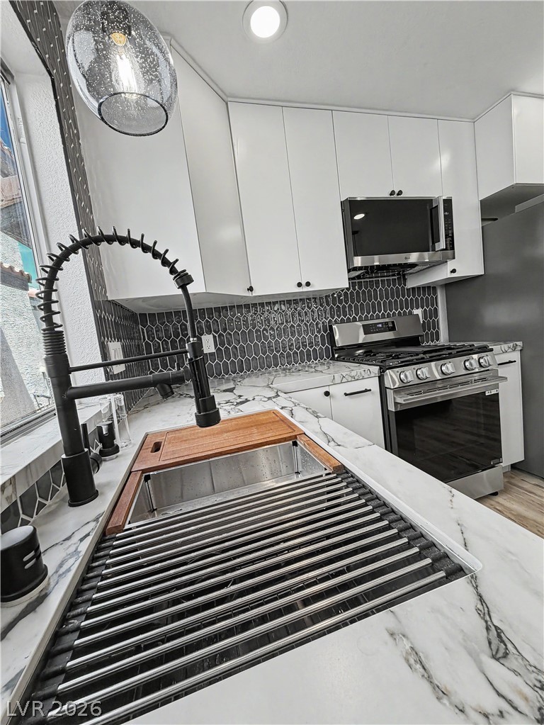 8977 Paige Rene Court Las Vegas, NV 89117 - Photo 9 of 31 An immaculate kitchen showcases bright white cabinetry, stainless steel appliances, and sleek marble countertops.