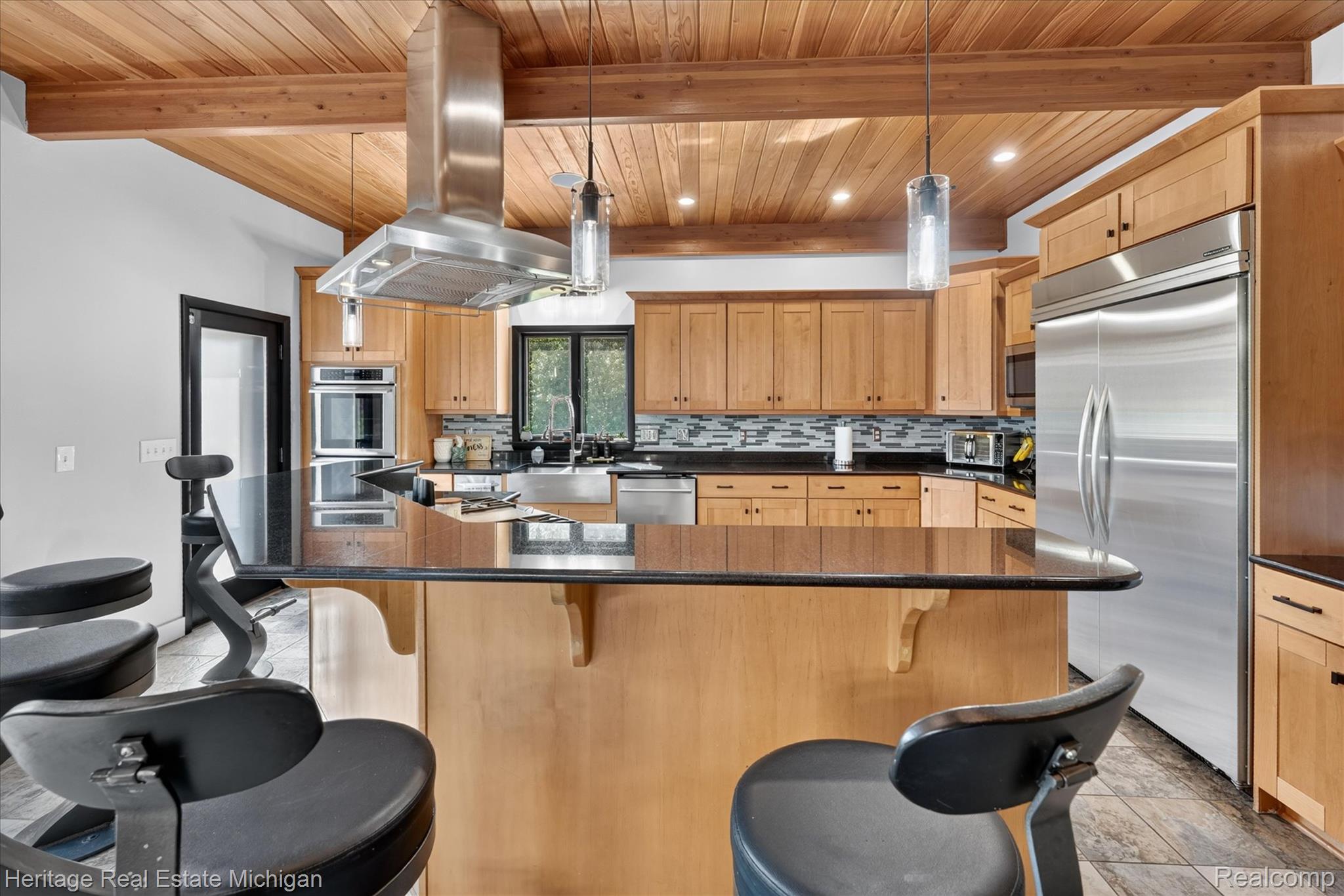 1888 Germany Road Williamston, MI 48895 - Photo 13 of 57 Kitchen featuring a large central island with a dark countertop, light wood cabinetry, stainless steel appliances, and a wood-paneled ceiling with exposed beams