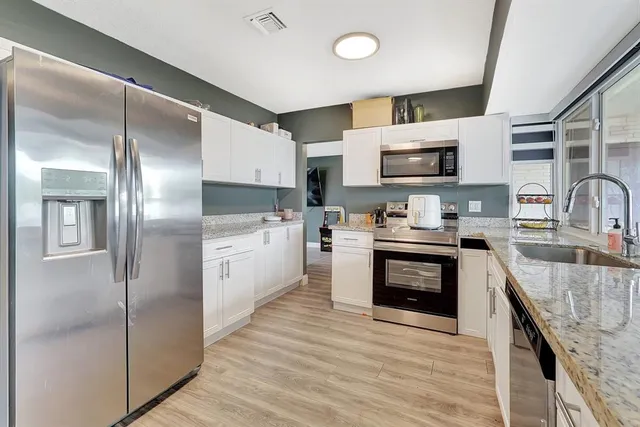 a kitchen with kitchen island granite countertop a sink cabinets and stainless steel appliances